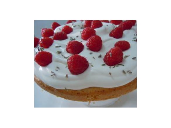 Bolo húmido de limão e alfazema com cobertura de natas frescas e framboesas.