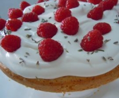 Bolo húmido de limão e alfazema com cobertura de natas frescas e framboesas.